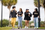 Four students walk on campus wearing UCF merchandise